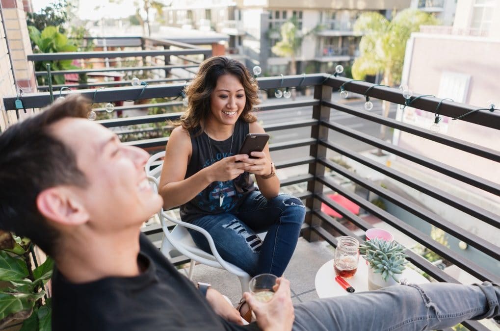 friends-hanging-out-on-a-balcony-using-mobile-phone_t20_8lbYnB